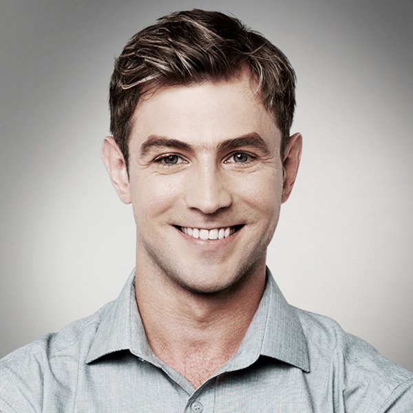 Smiling man with light skin, wearing a blue shirt.